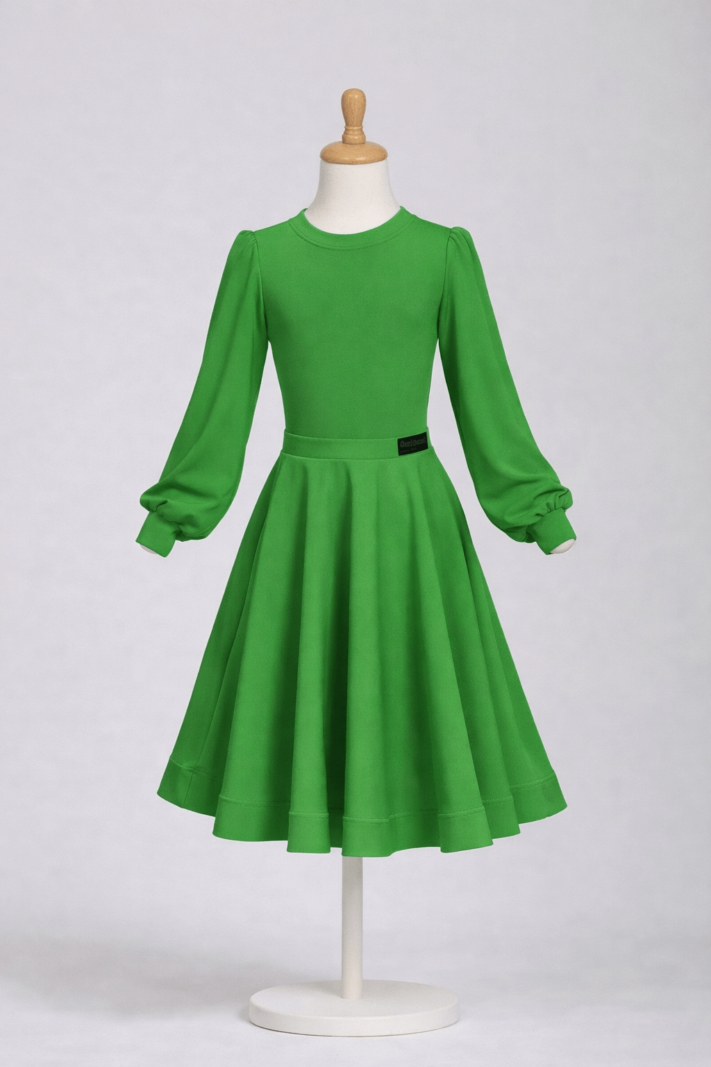 Green dress on a mannequin against a white background Green juvenile ballroom competition set with bodysuit and 360° knee-length skirt for Latin and Standard dancing