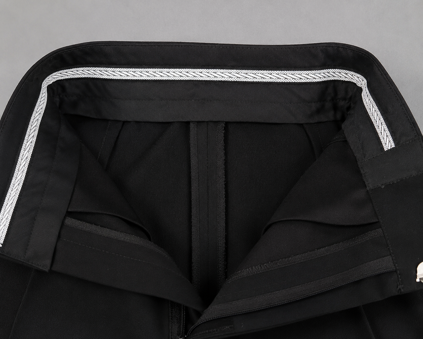 Close-up of boys black Standard Ballroom dance trousers with structured waistband, front pleats, satin side stripe and Diamond Fashion branding