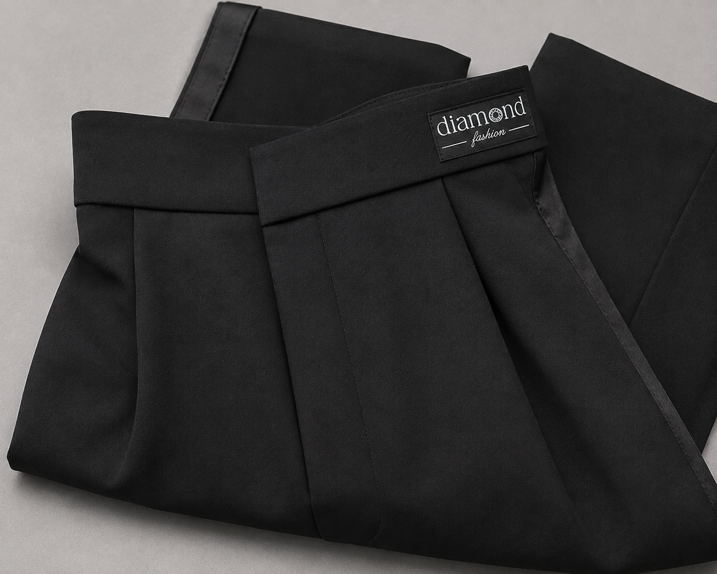 Close-up of boys black Standard Ballroom dance trousers with structured waistband, front pleats, satin side stripe and Diamond Fashion branding