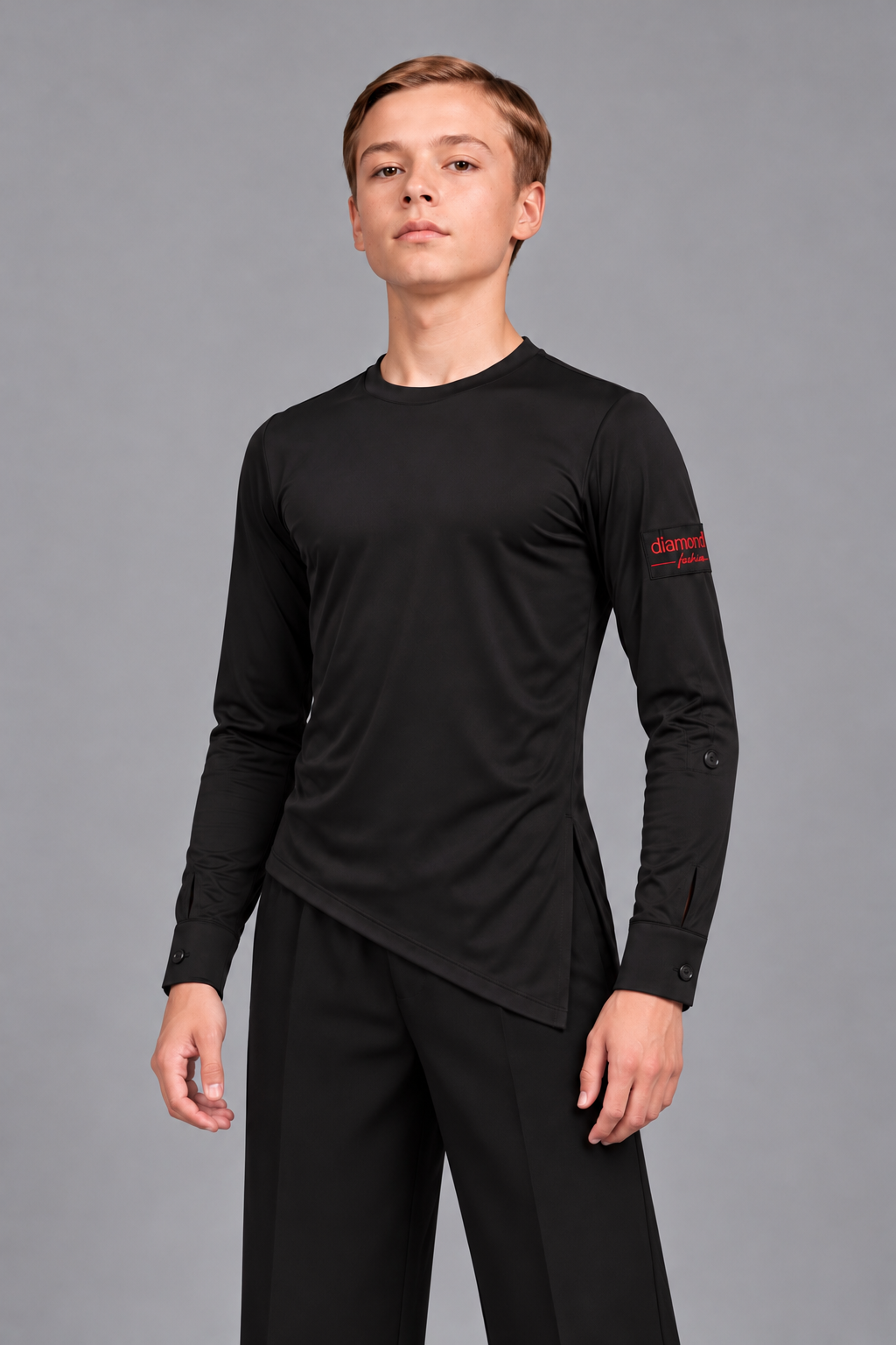 Boy wearing a Diamond Fashion black stretch Latin and ballroom dance top with an asymmetric hem, long sleeves and buttoned cuffs, front view