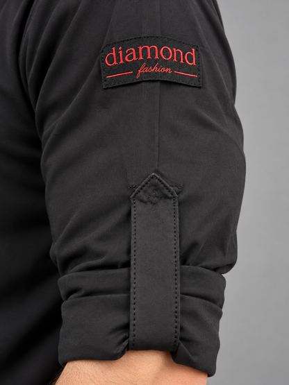 Close-up of a Diamond Fashion black men’s dance top with a rolled sleeve, fastening tab and red embroidered logo.