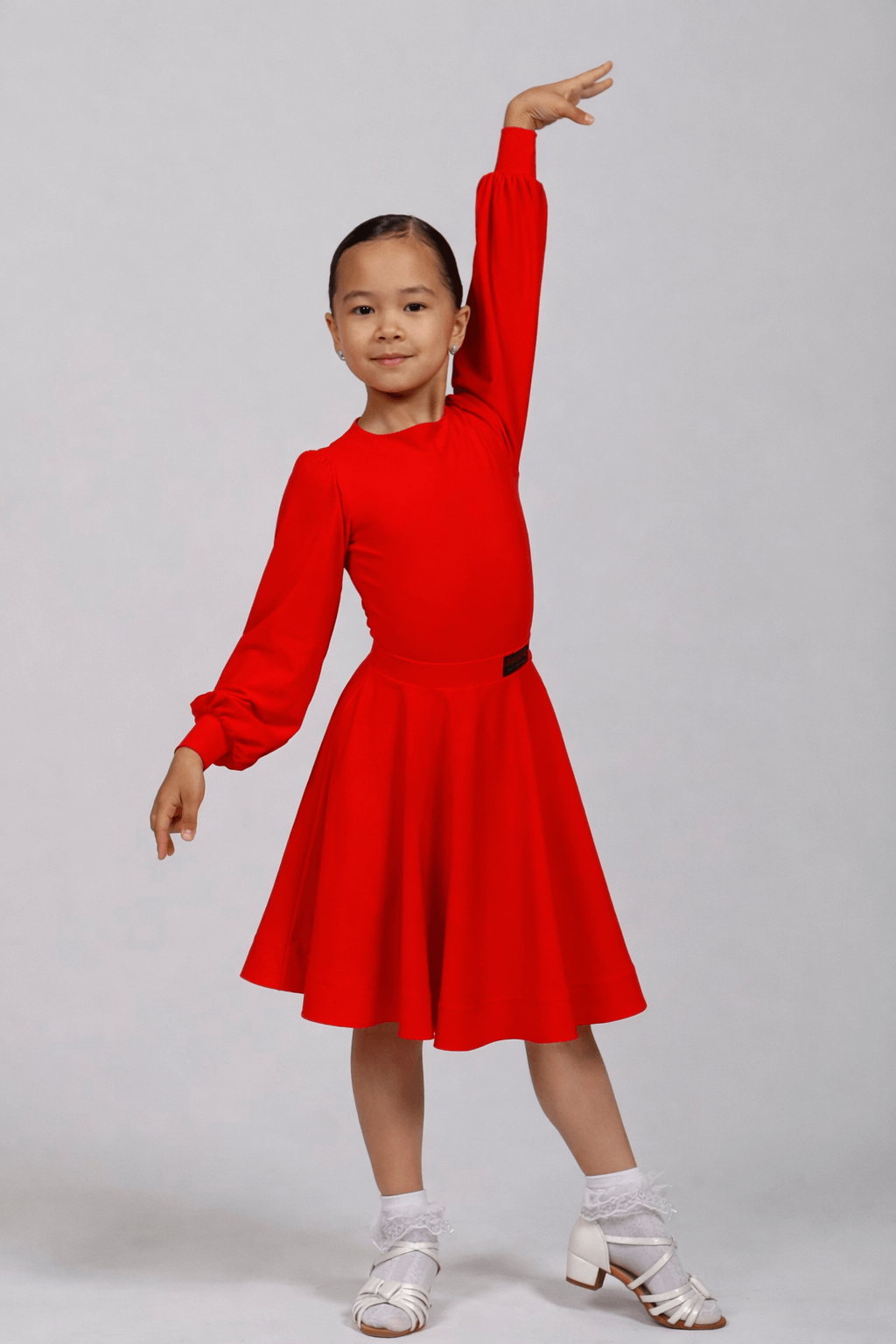 Young girl wearing a red dress posing against a plain background Juvenile ballroom competition dance set with bodysuit and knee-length 360 circle skirt in red, WDSF approved, suitable for Latin and Standard
