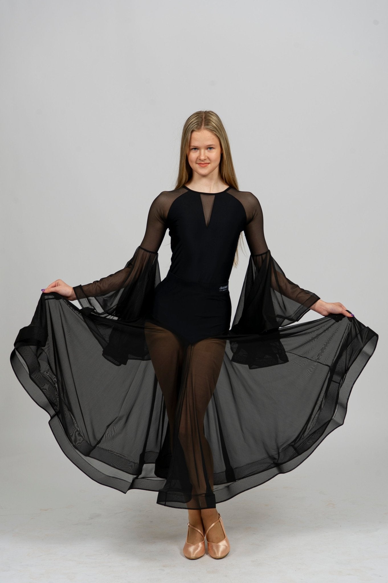 Elegant dancer in a black dance bodysuit with flowing sleeves and a sheer skirt, showcasing movement and grace.