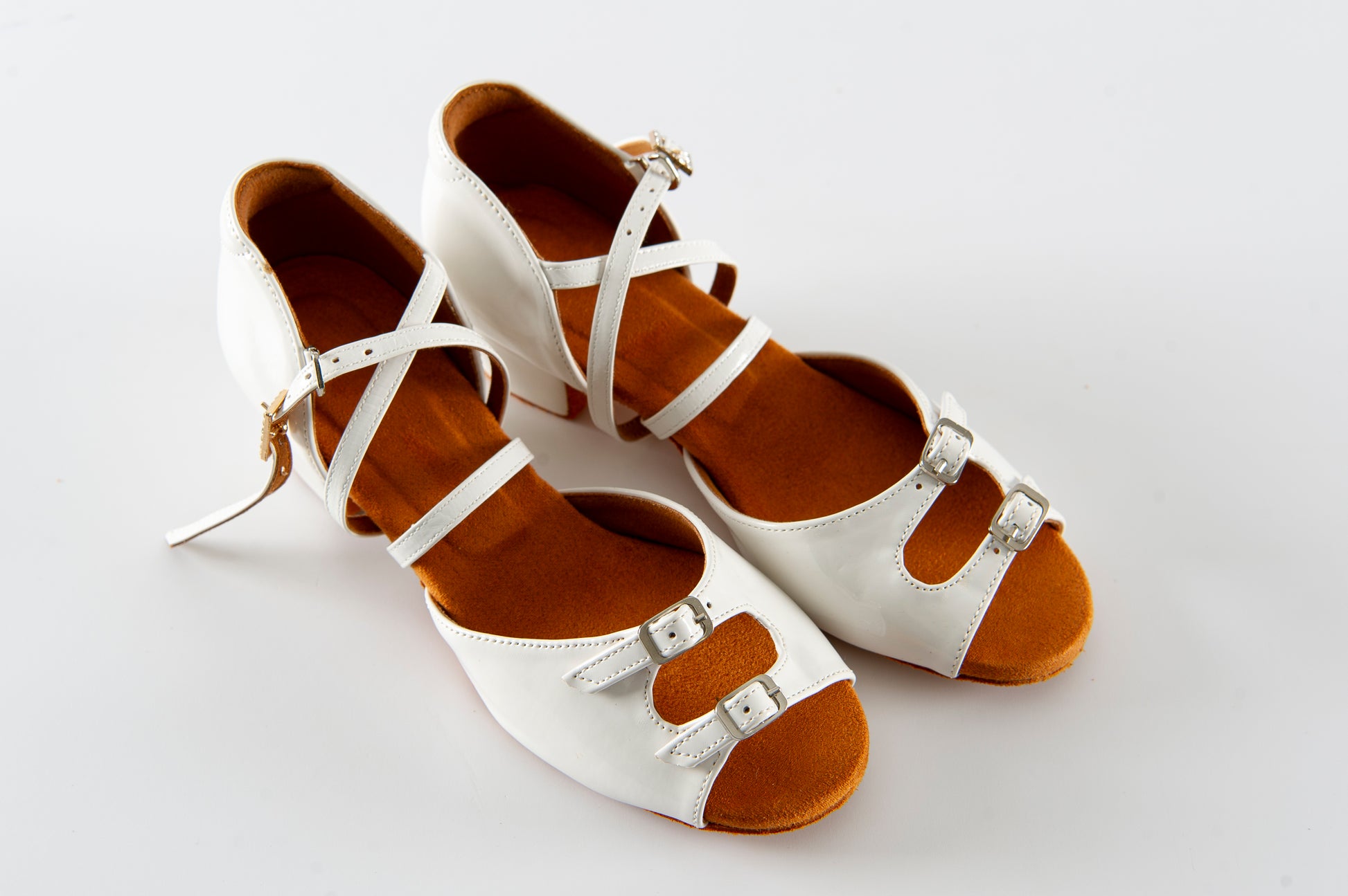 White ballroom dance shoes for girls with leather straps and suede sole, photographed on a light background