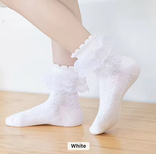 White lace dance socks for girls with ruffled trim, worn during dance practice on a wooden floor